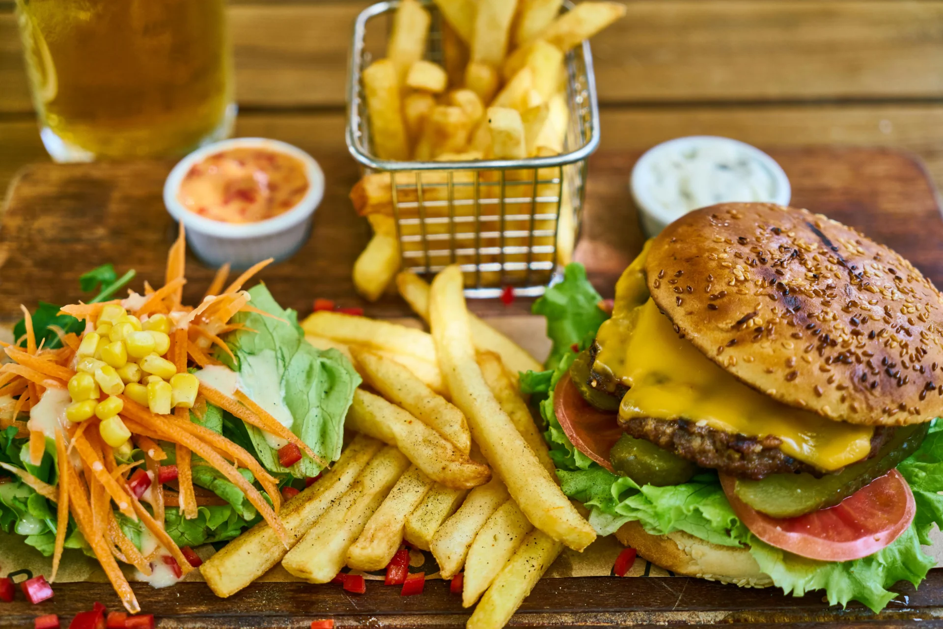 Cheeseburger with fries and fresh salad served on a wooden board as part of a marketing strategy for fast food restaurant branding