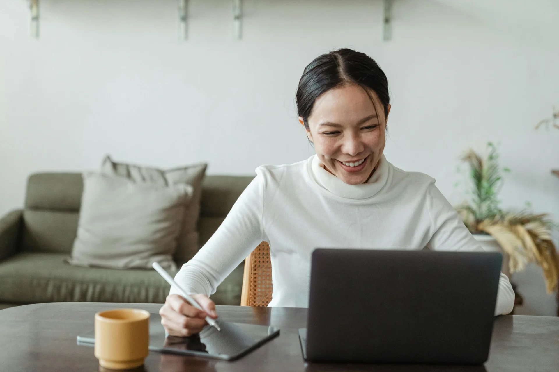 Smiling woman working on a laptop and tablet, researching what are semantic terms in SEO for content optimization.