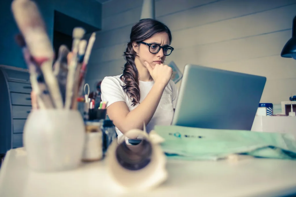 A focused woman looking at a laptop with a hand on her chin, reflecting on the possible ranking volatility causes after a major search engine update.