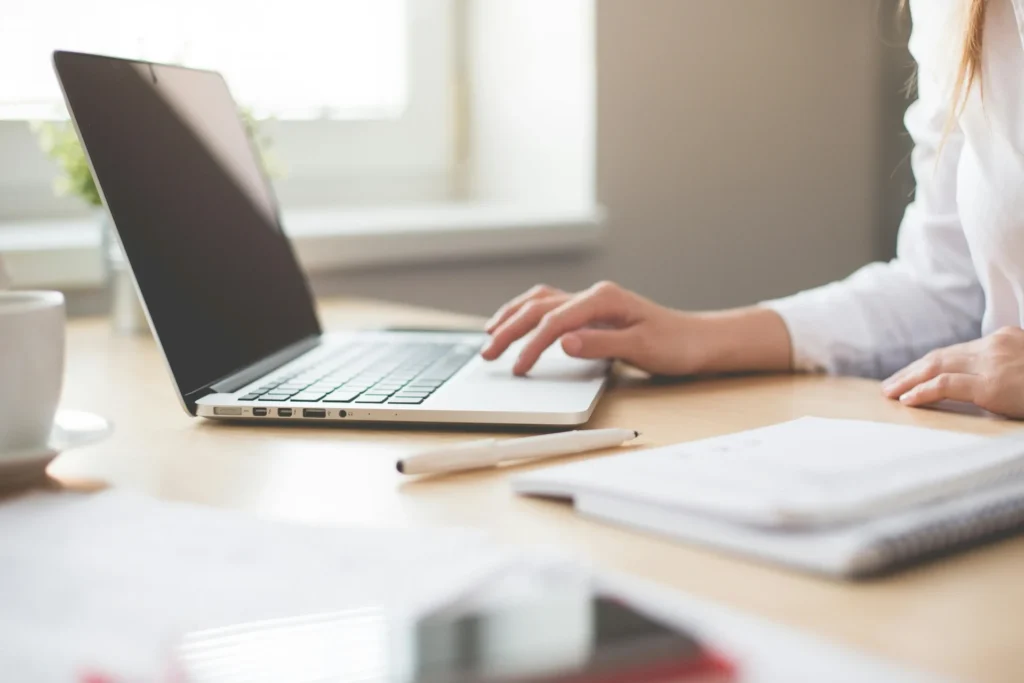 Person working on a laptop at a desk with documents, reflecting personalized search engine research and content optimization.