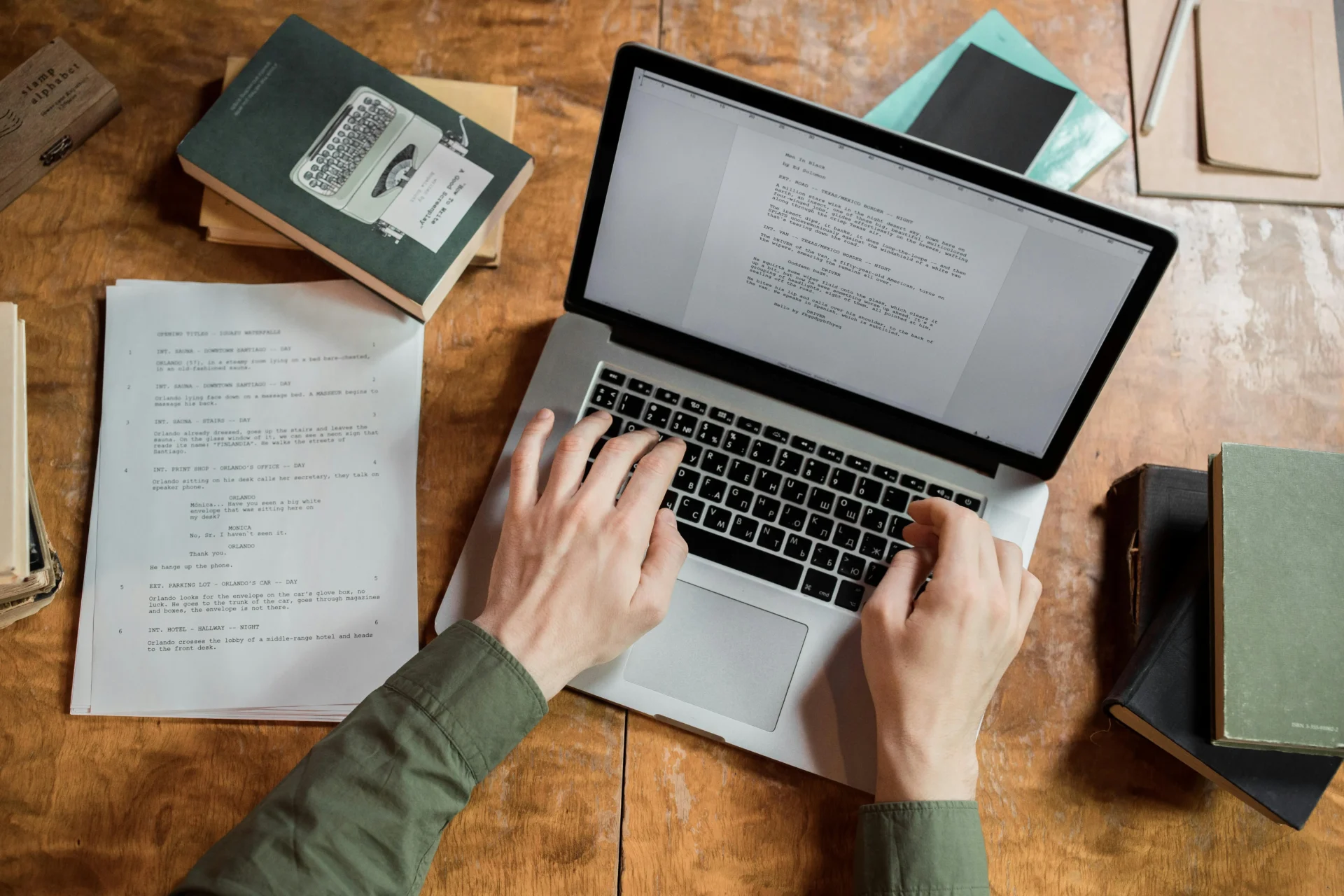 Overhead view of hands typing on a laptop with documents scattered around, working to address ranking volatility causes by updating and improving content.