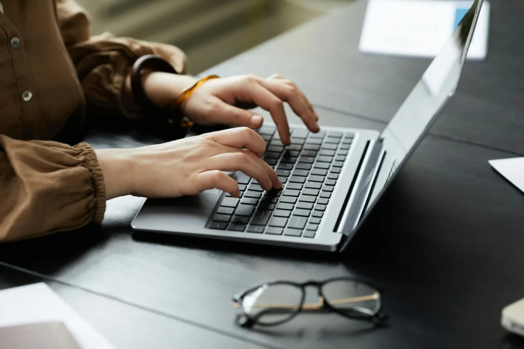 A close-up view of a person using a laptop to review colorful data charts and analytics to optimize organic social reach during a team meeting.