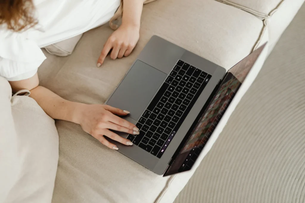 Woman pointing at a laptop screen while working on a sofa, illustrating potential indexing delay factors and technical SEO issues.