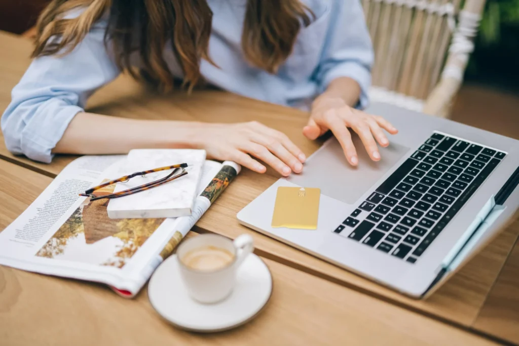 A person using a laptop and a gold credit card at a wooden table with a coffee cup and magazine to demonstrate page intent alignment in online shopping.