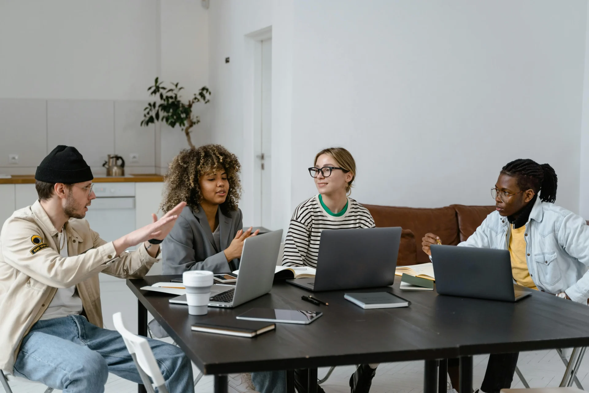 A diverse group of young professionals working on laptops at a table, discussing how freshness vs relevance affects digital content strategy.
