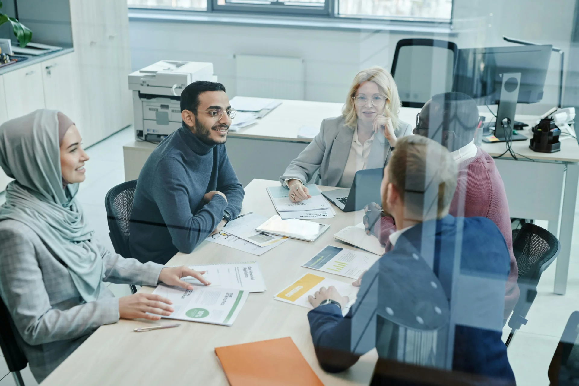 A diverse group of professionals in a bright, modern office sitting around a conference table discussing data reports for B2B trust building.