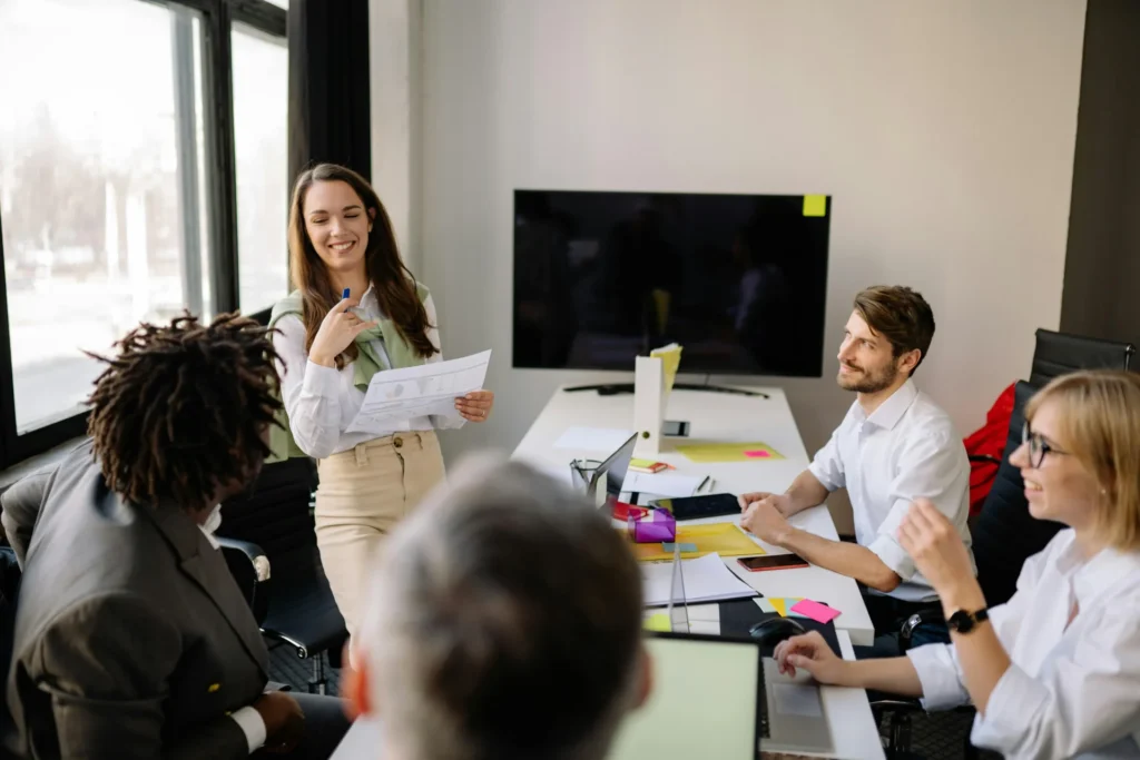 A professional woman leads an office meeting with charts, demonstrating the balance of freshness vs relevance in data reporting.