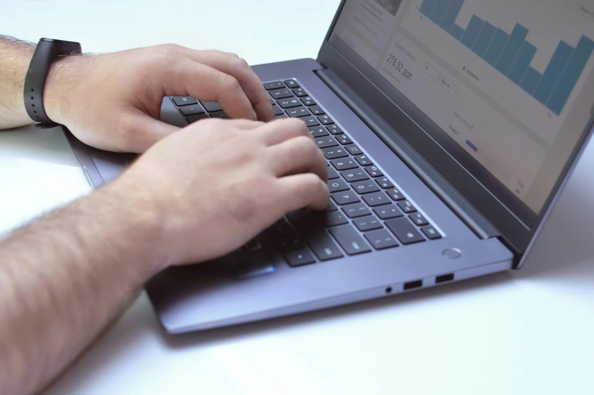 Close-up of a marketing specialist typing on a laptop while analyzing dashboard data to evaluate how algorithms prioritize content in search results.
