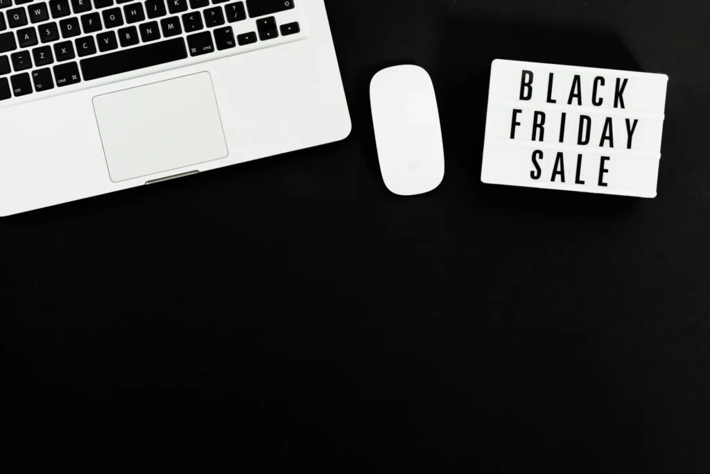 Laptop and Black Friday sale sign on desk illustrating black friday email campaign psychology and seasonal promotional strategy planning.
