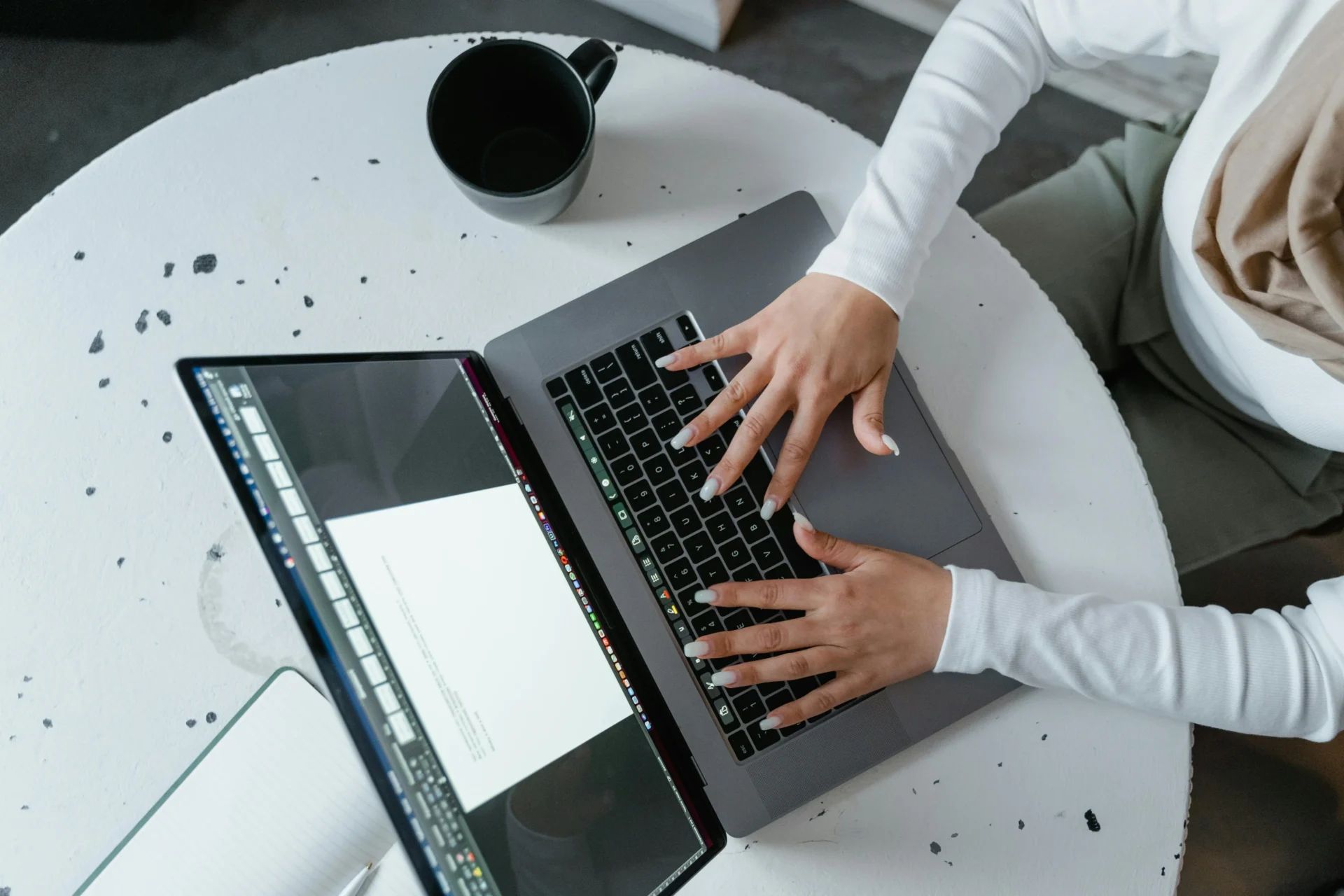 A person with long white nails typing on a laptop keyboard to analyze keyword intent classification.