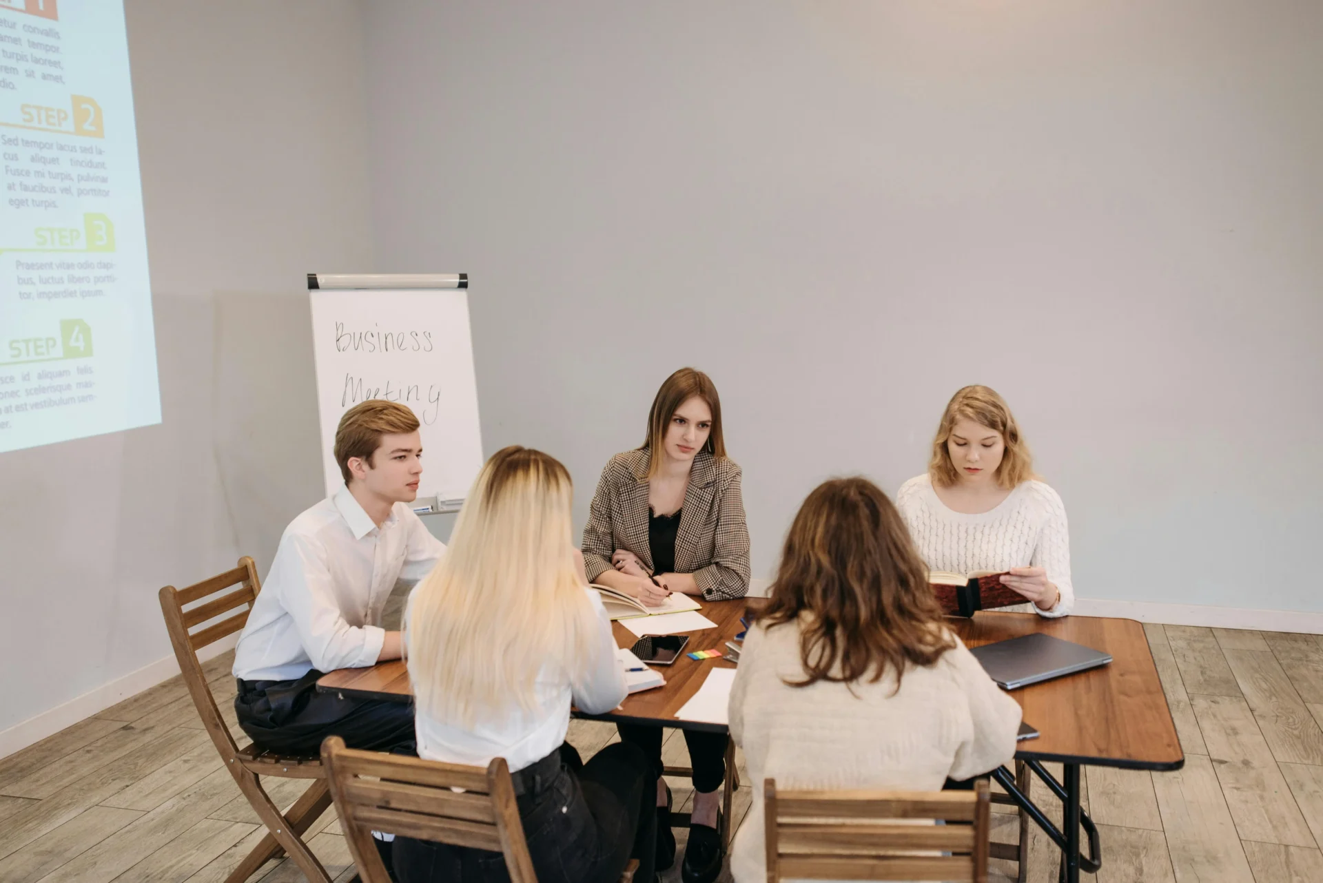 A group of young professionals sitting around a wooden table discussing evergreen vs trending content strategies during a business meeting.