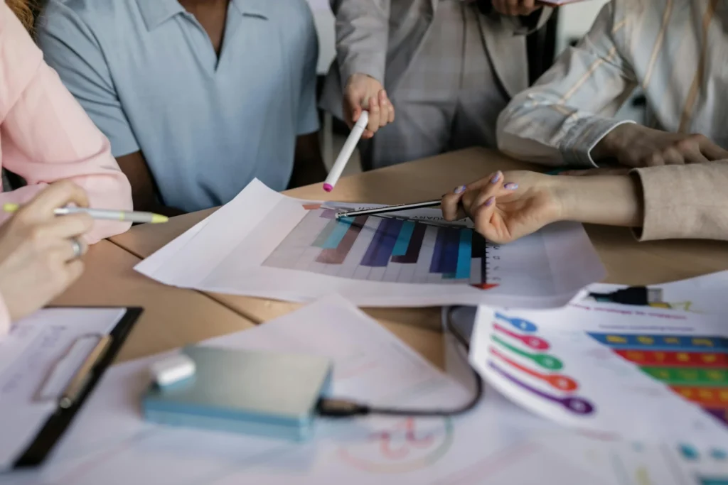 Group discussing charts and pointing at printed graphs, illustrating map pack algorithm basics and data analysis