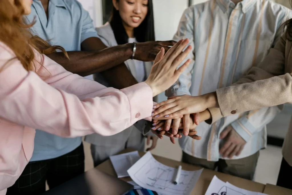 Diverse team stacking hands together during a marketing meeting discussing pipeline acceleration strategies for business growth