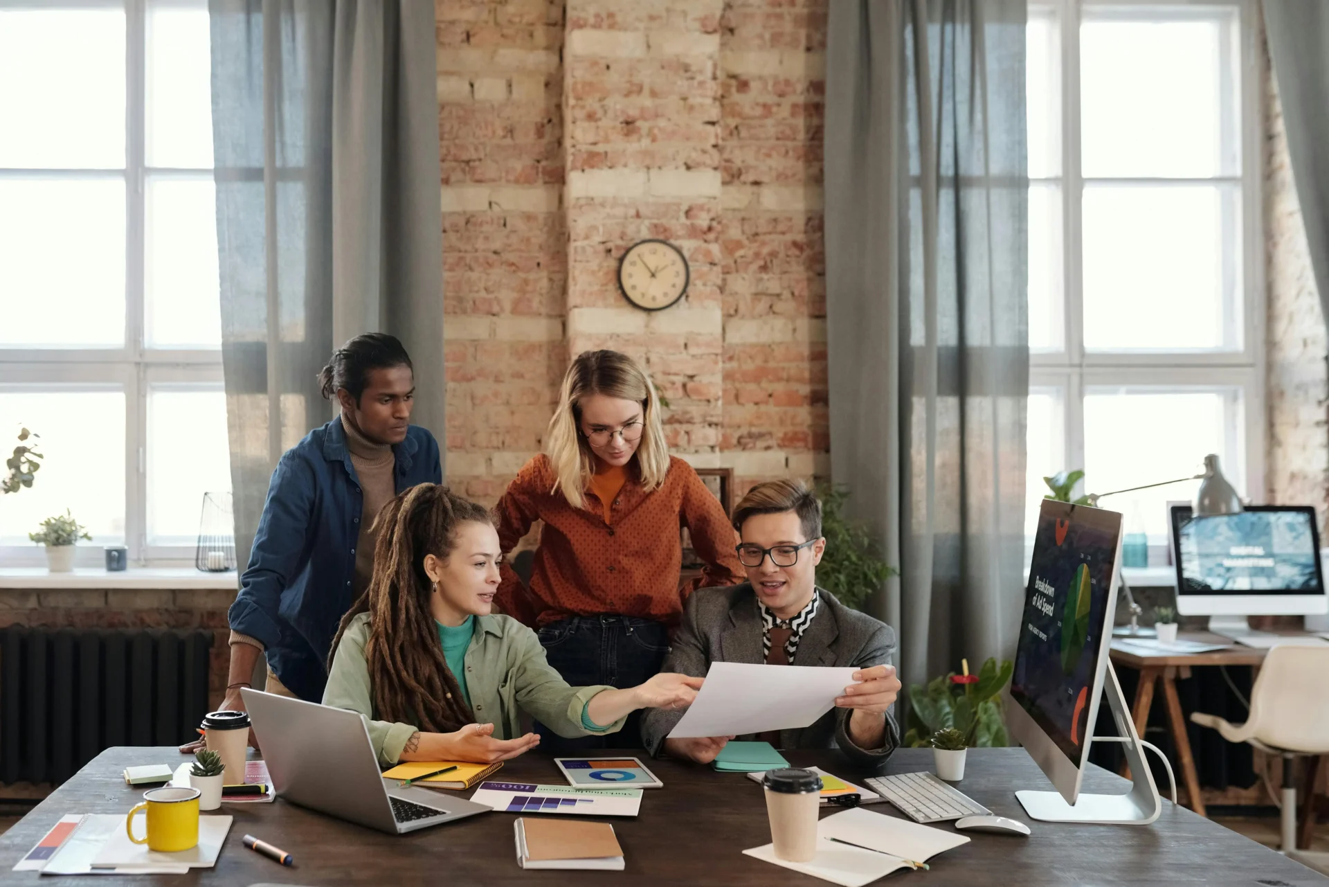 Marketing team collaborating around a desk reviewing documents and analytics while planning a multi stakeholder marketing strategy