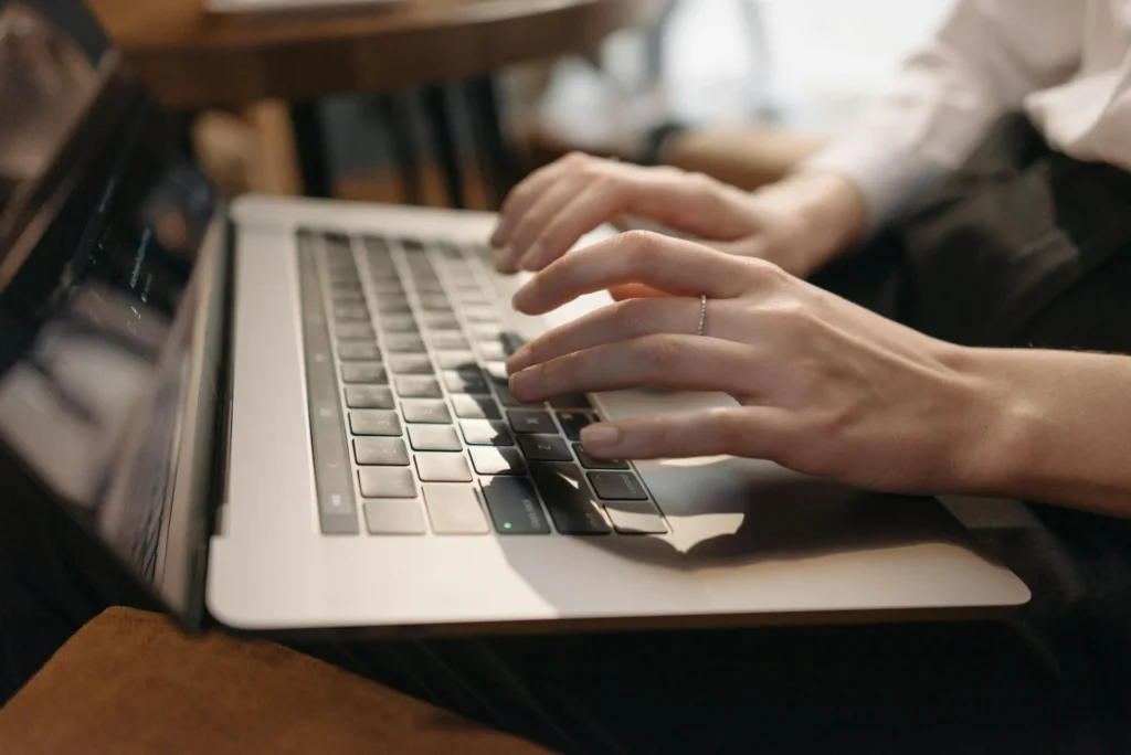 Close-up of hands typing on a laptop keyboard, symbolizing decentralized search trends and online activity