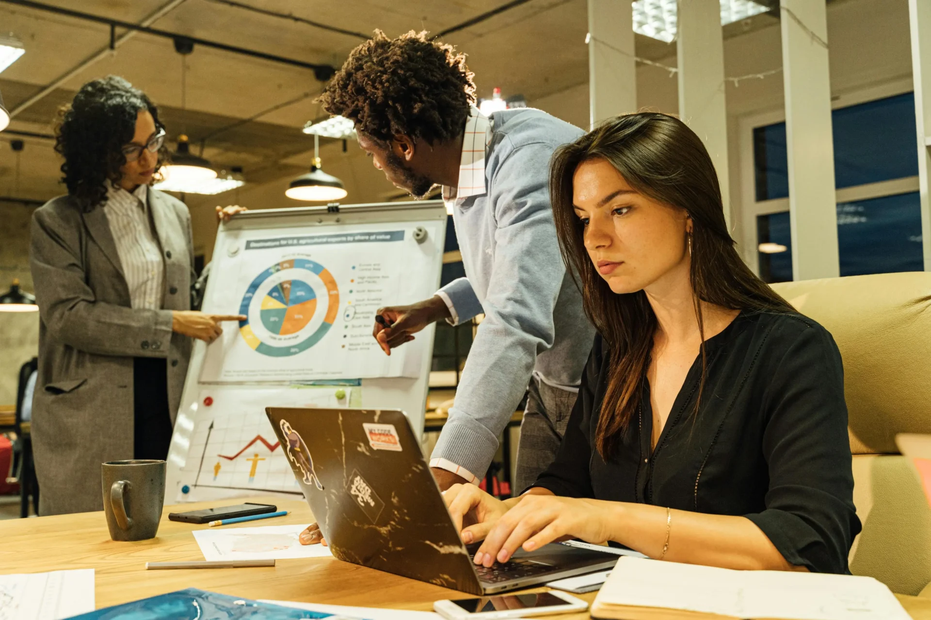 Team collaborating around a laptop and presentation board, representing map pack algorithm basics and strategic planning