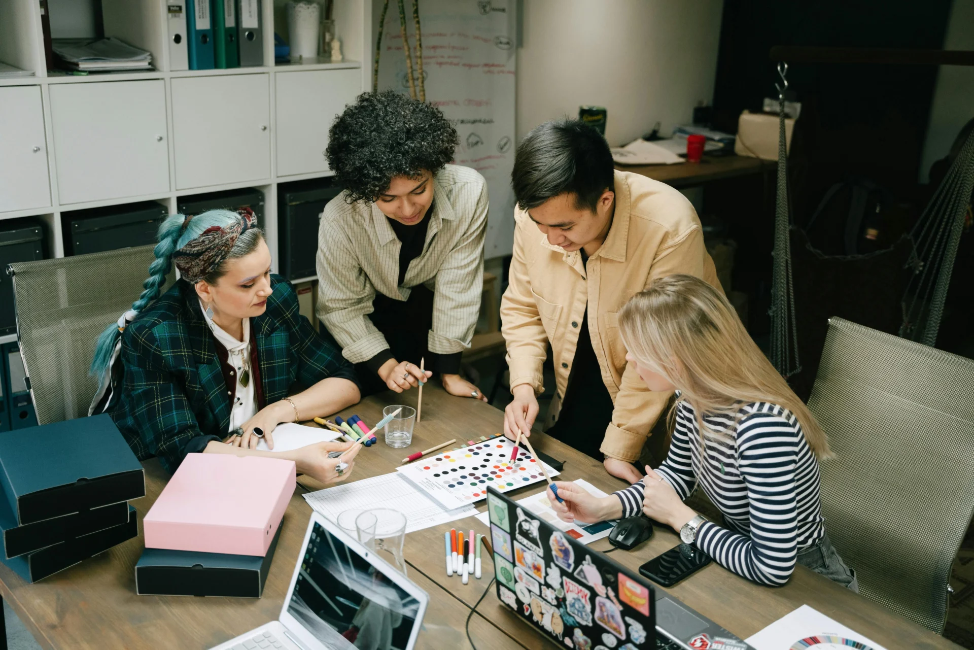 Marketing team pointing at colorful charts and data reports on a table while planning an AI visibility platform strategy.