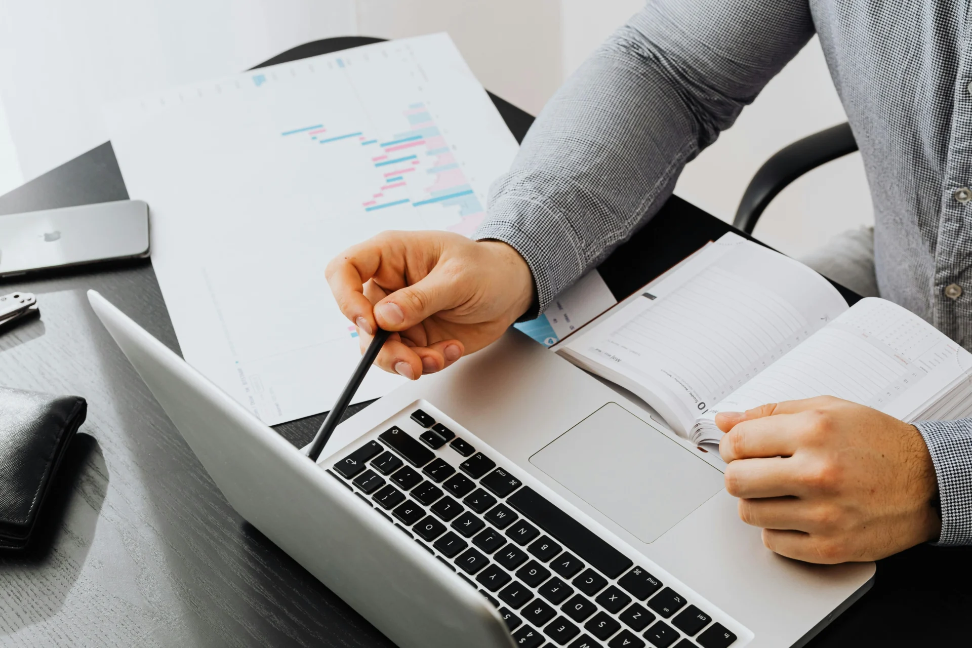 Professional pointing at a bar chart next to a laptop and notebook while analyzing AI Overview in Google search results.