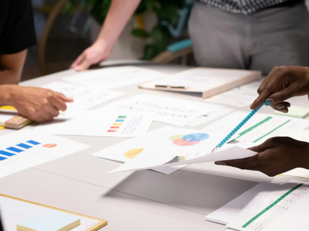 Diverse creative team collaborating around a table with markers and color swatches while building an AI visibility platform strategy.