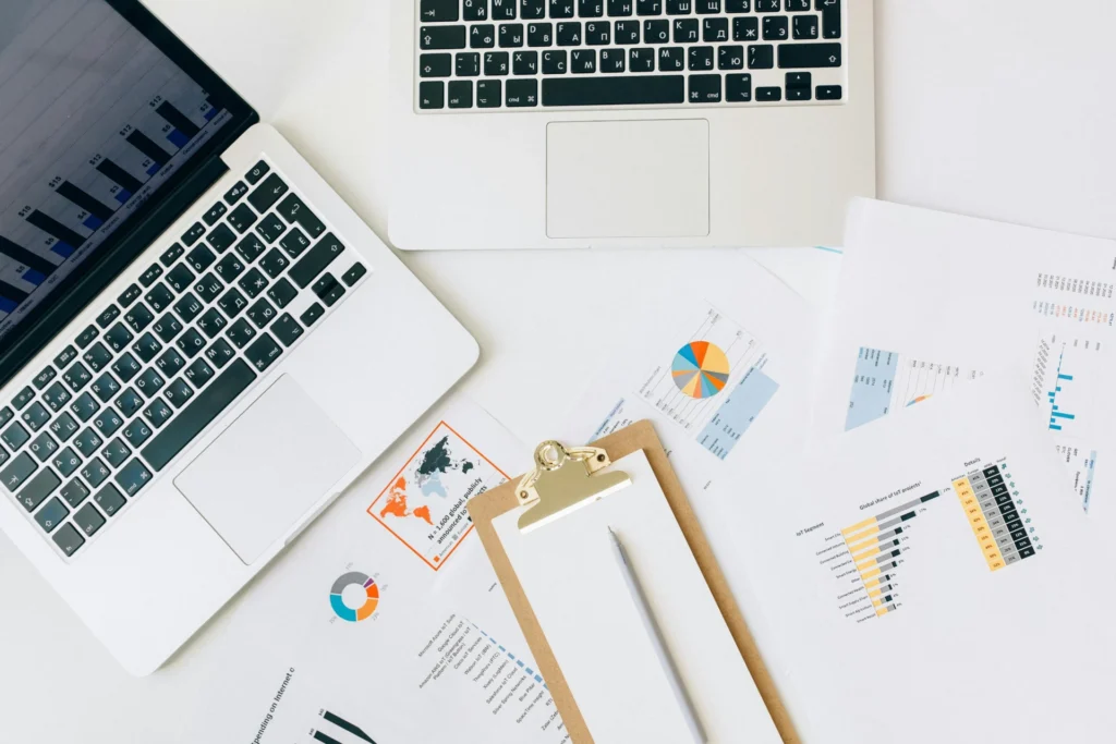 Flat lay of two laptops and printed data charts on a desk representing research on AI Overview in Google.