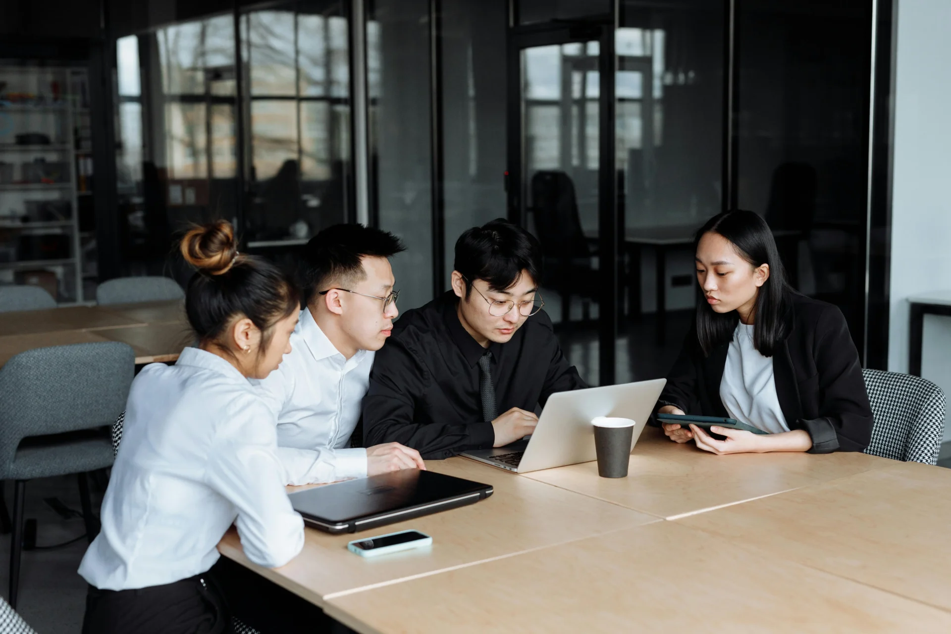 Professionals collaborating on laptop to optimize content for AI in modern office setting