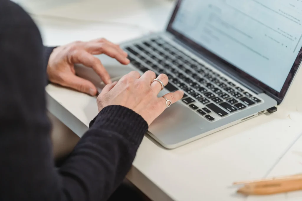 Person typing on a laptop researching how to improve visibility in Google AI Overviews for their website.
