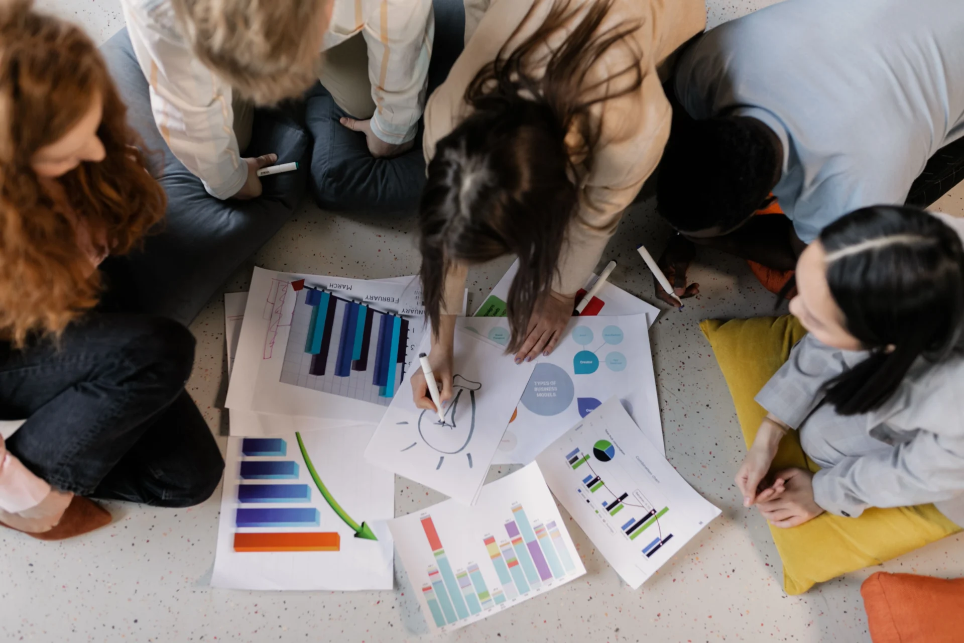 Diverse marketing team reviewing data charts and reports while using tools for tracking brand mentions in AI search results during a collaborative strategy session