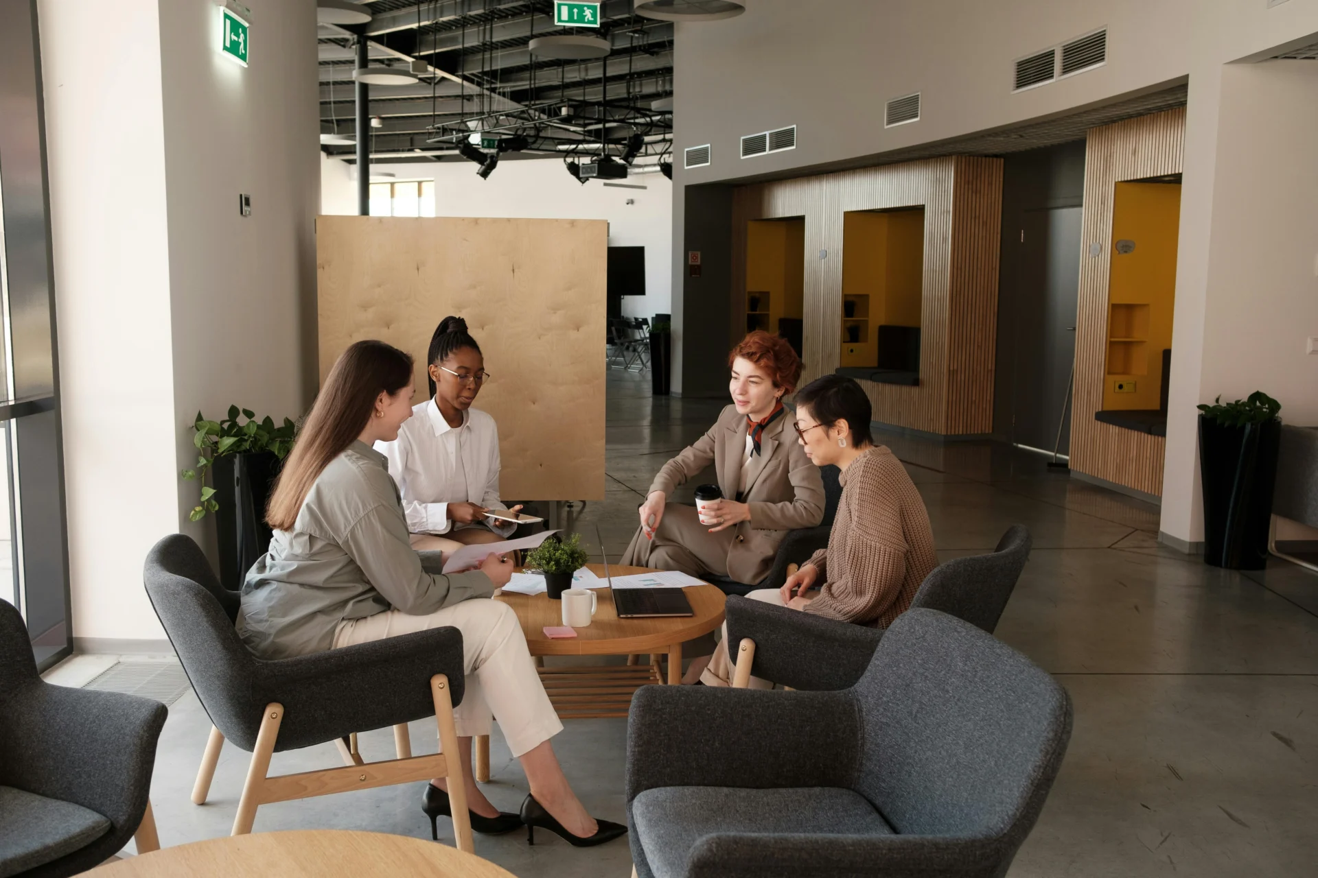 Diverse marketing team collaborating around a conference table with laptops, creating content for AI readability during a strategy meeting in a modern office.