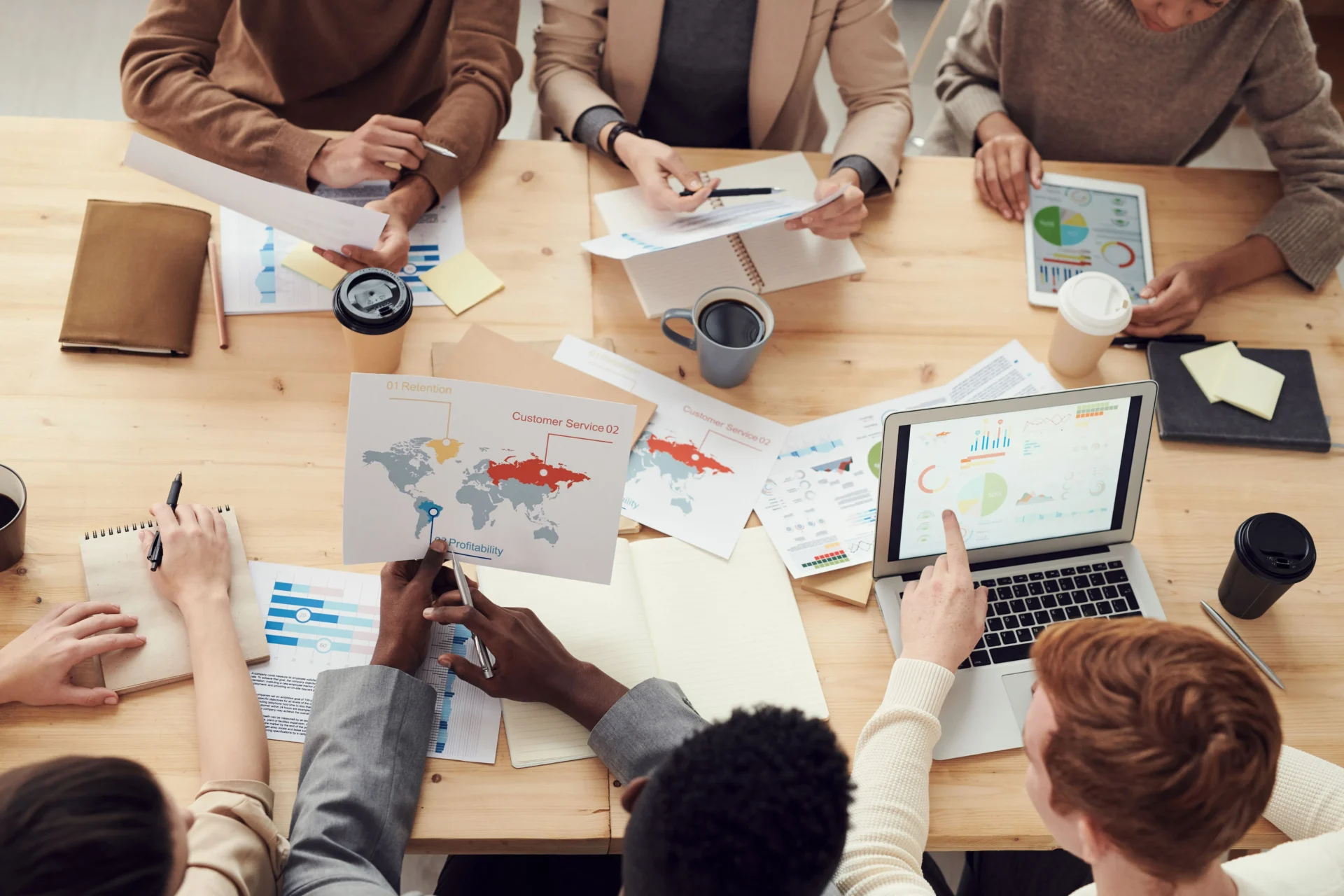 Diverse marketing team reviewing global analytics maps and digital dashboards to develop a brand strategy built around organic GEO vs paid AI visibility insights.