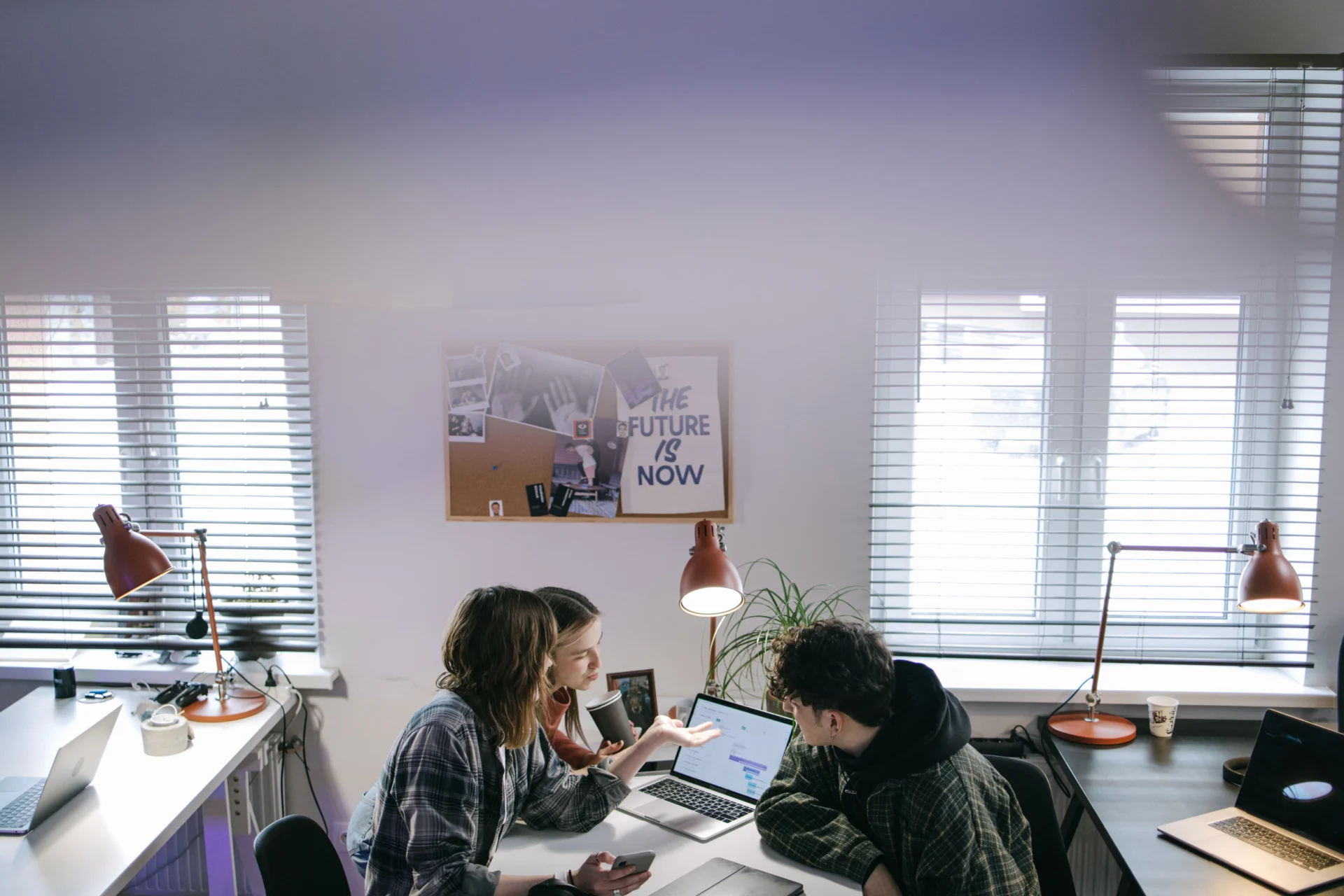 Three digital marketing professionals collaborating on a laptop to discuss how to identify content gaps for AI visibility.