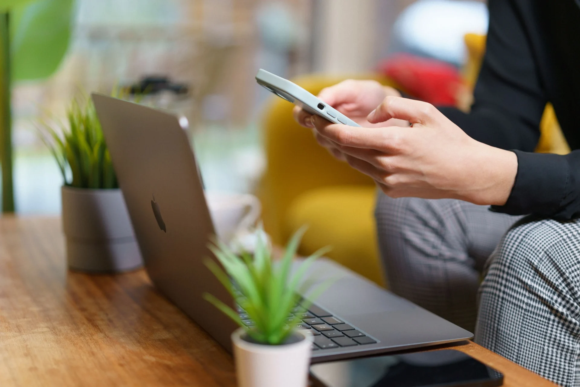 Marketing professional using a smartphone and laptop to research AI featured snippets strategies in a modern workspace.