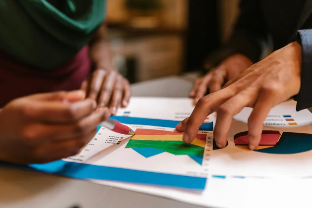 Marketing analysts pointing at colorful performance charts and data graphs while using tools for tracking brand mentions in AI search results to refine brand strategy