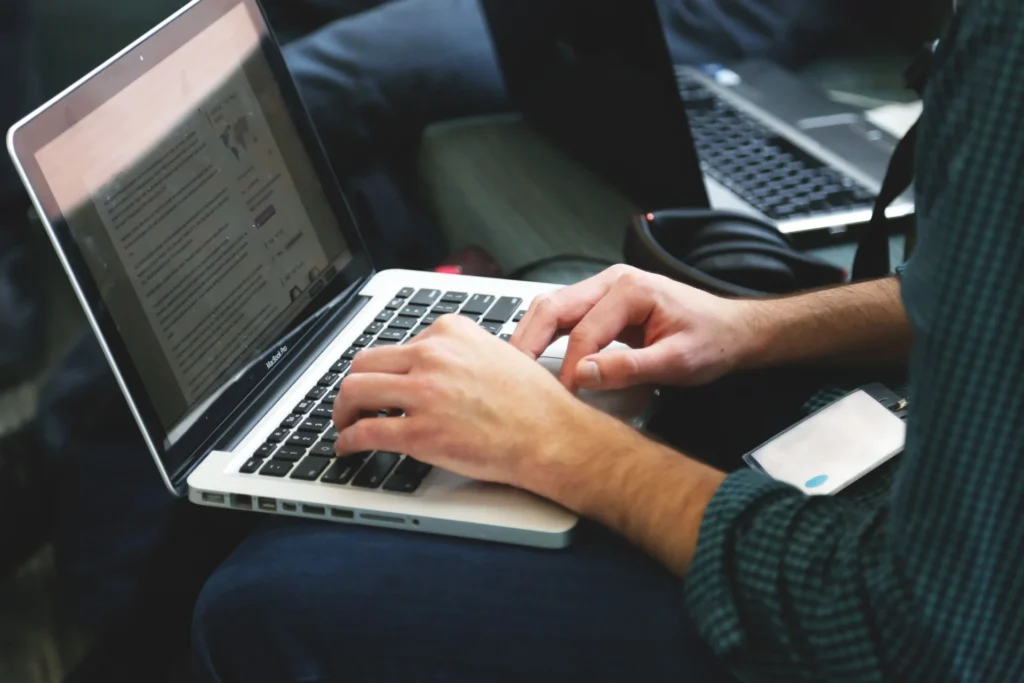 Digital marketer typing on MacBook Pro while optimizing web content for GEO for small businesses.