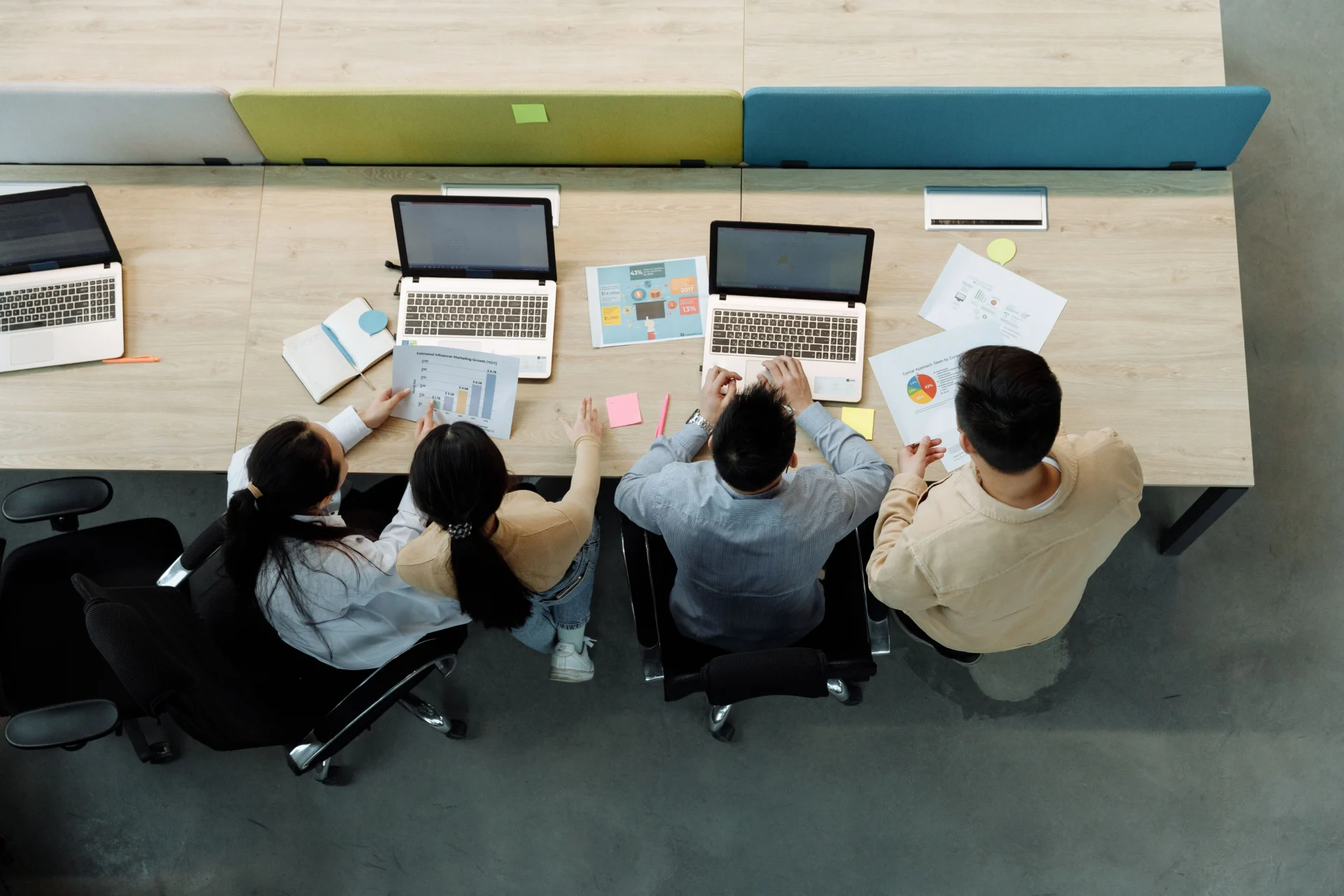 Marketing team collaborating with laptops and data reports to develop an AI and voice search optimization strategy.