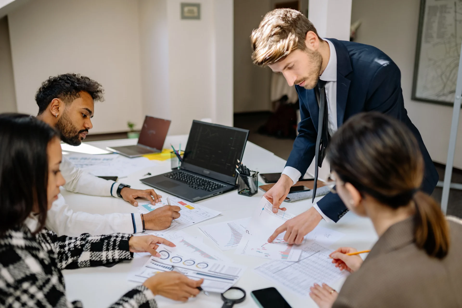 Diverse marketing team reviewing printed analytics reports at conference table while working through a GEO implementation checklist.
