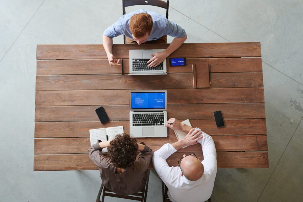 Overhead view of marketing professionals discussing AI strategic visibility outline on laptops