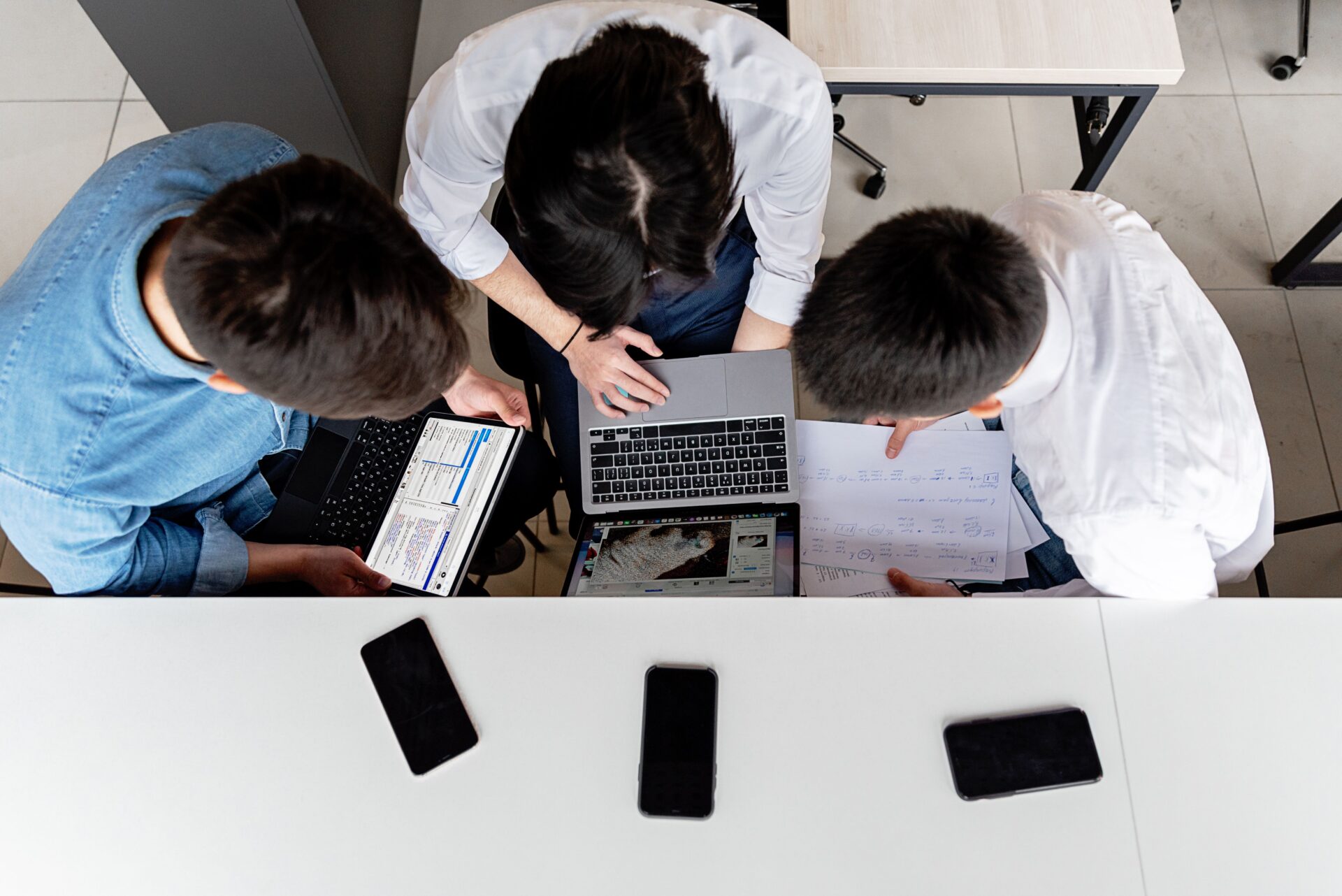 Overhead view of team analyzing data on laptops showing how brands manage reputation across AI platforms