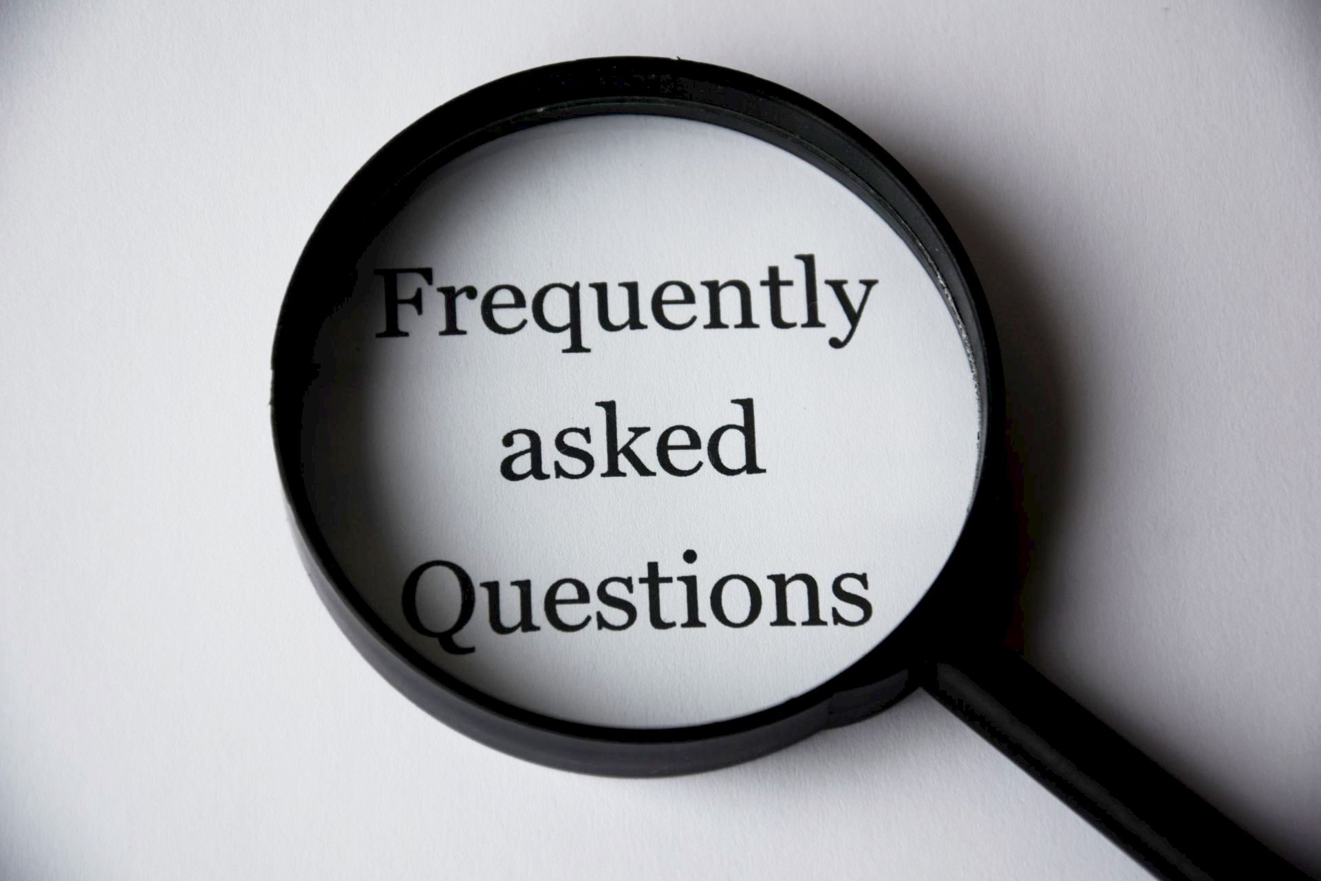 Magnifying glass highlighting frequently asked questions text, showing how to optimize FAQ pages for AI answer engines