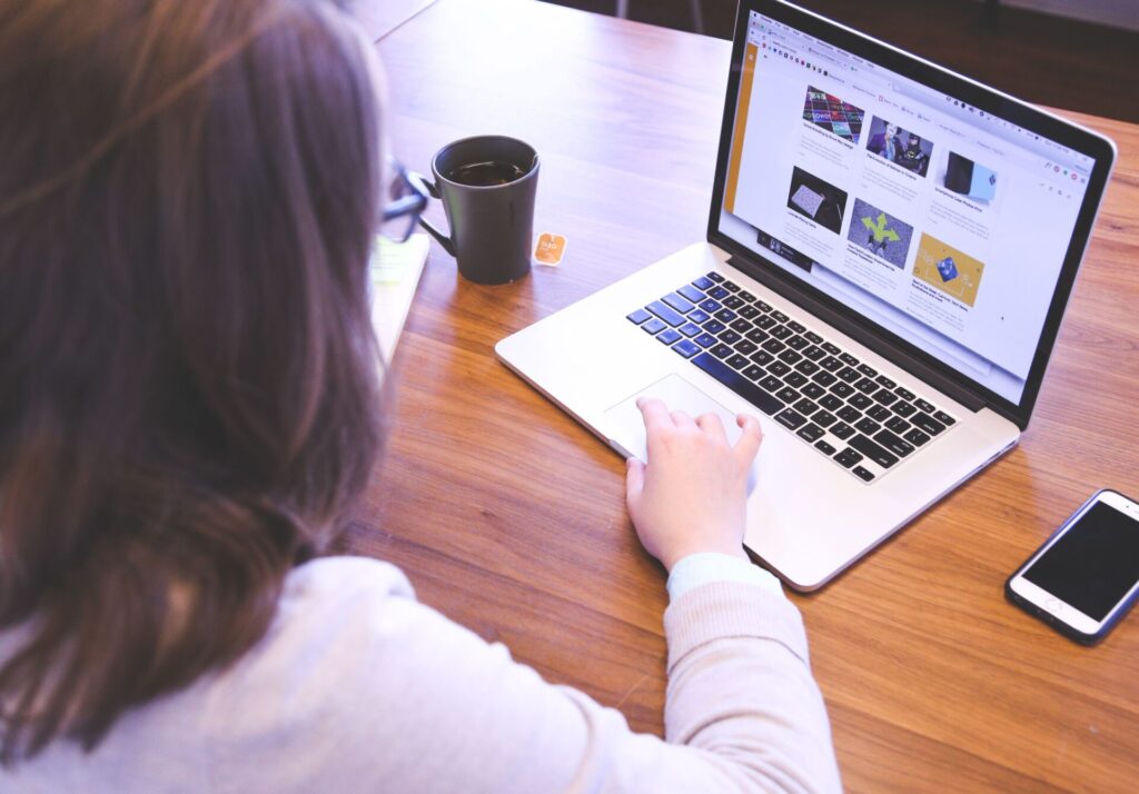 Woman browsing design website on laptop, researching how to make your website AI-search ready
