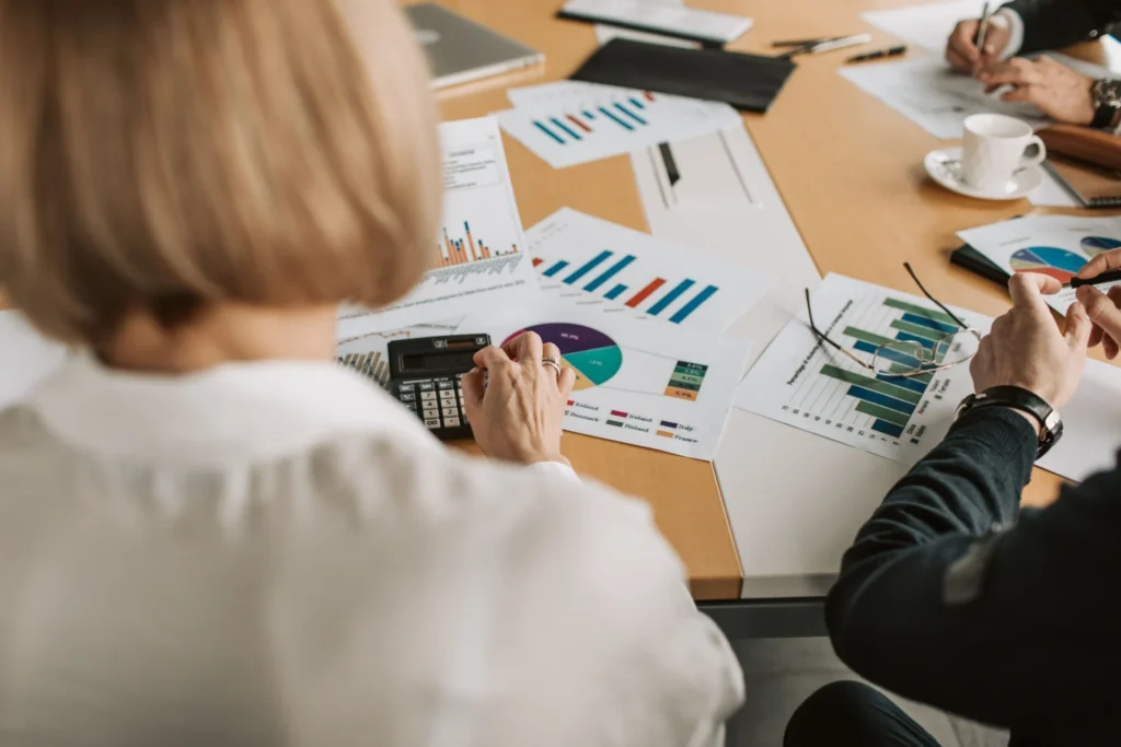 Analysts examining printed performance graphs to support AI-assisted keyword research for GEO strategy.