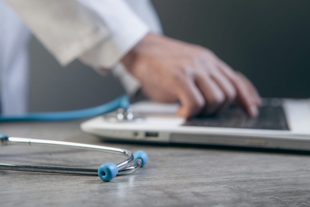Doctor using laptop with stethoscope on desk, supported by best GEO agency for healthcare