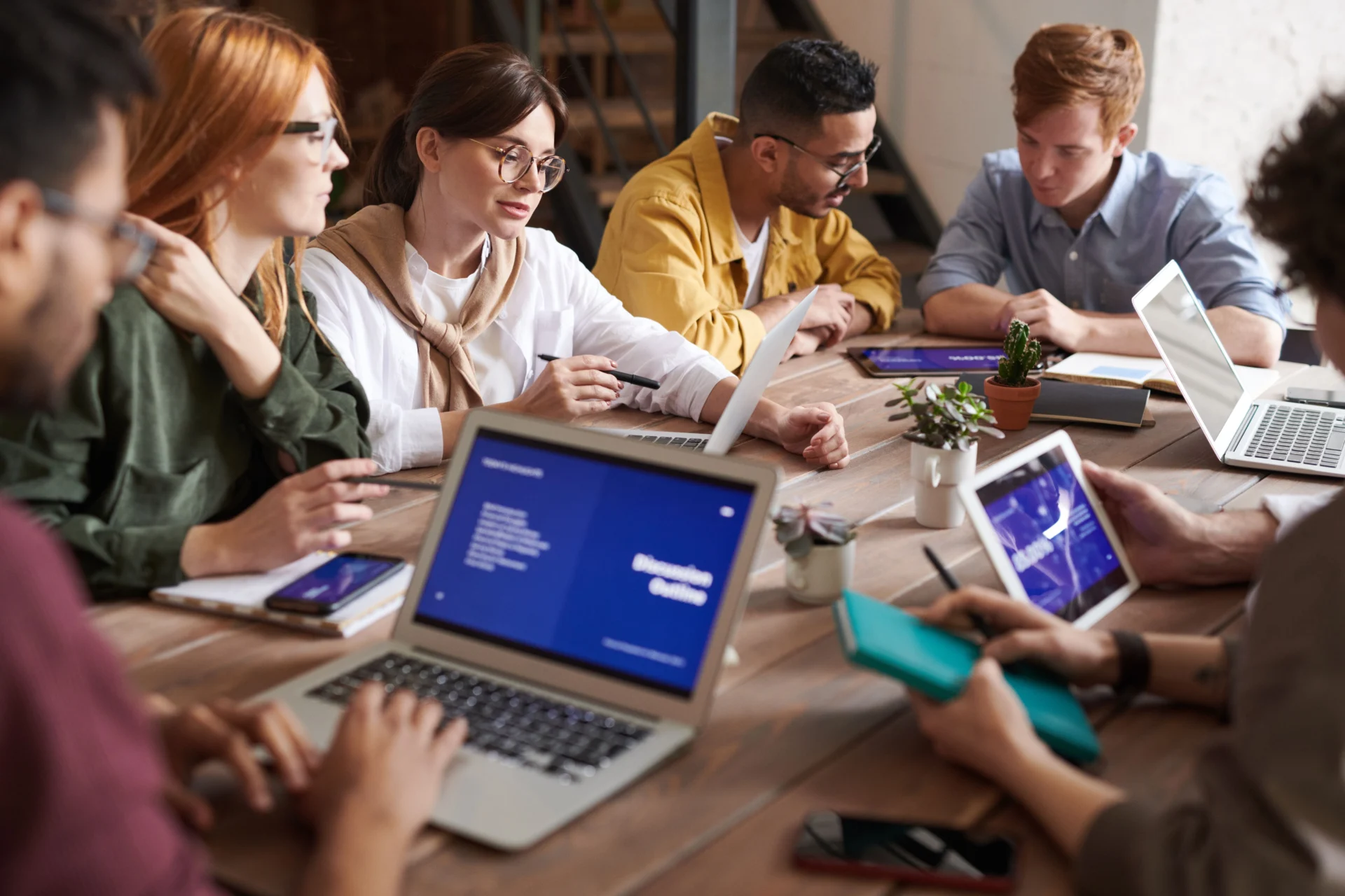 Marketing team gathered around laptops and tablets discussing an internal linking strategy for GEO