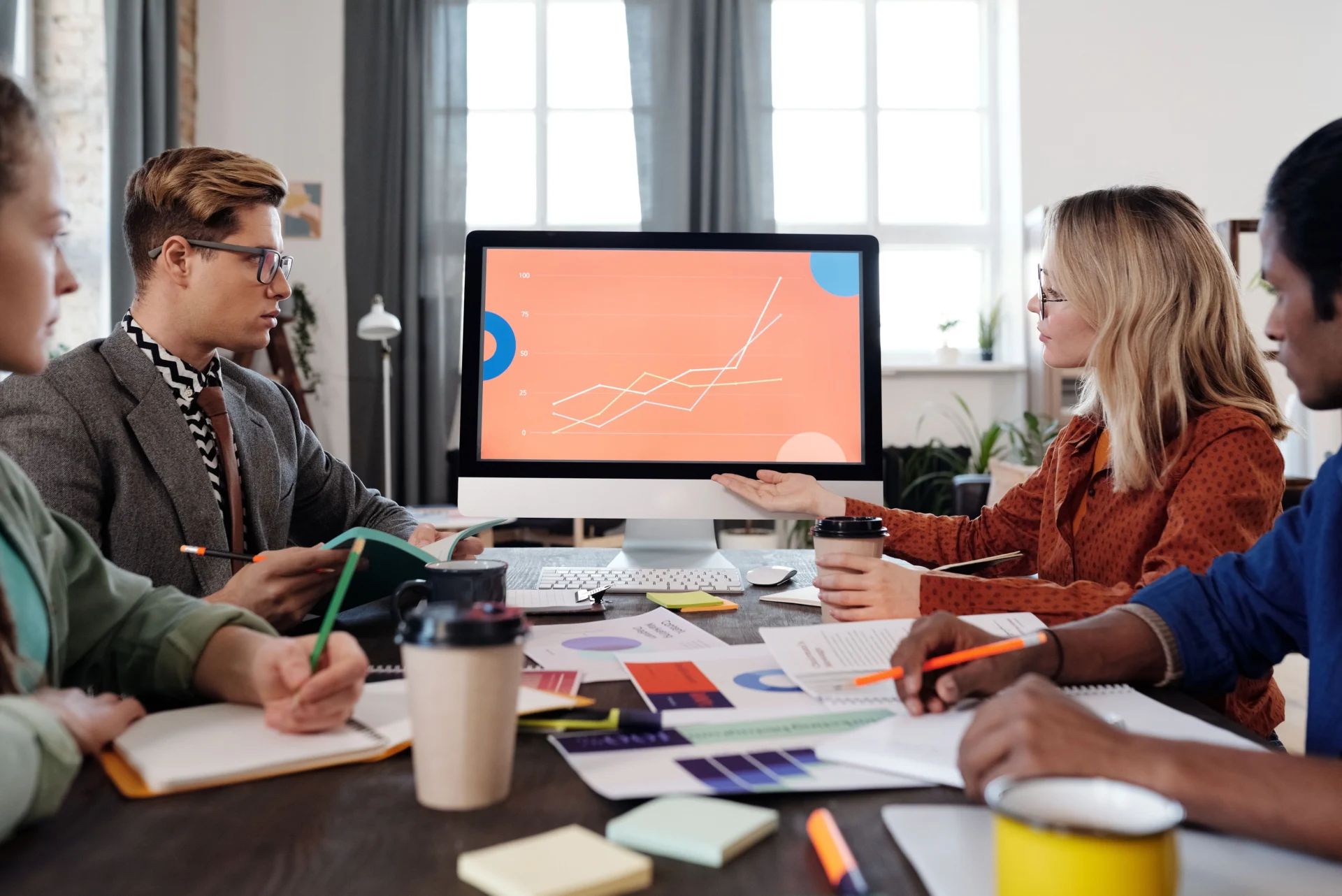 Marketing team reviewing performance charts on a monitor during a strategy meeting about how to optimize testimonials for AI visibility