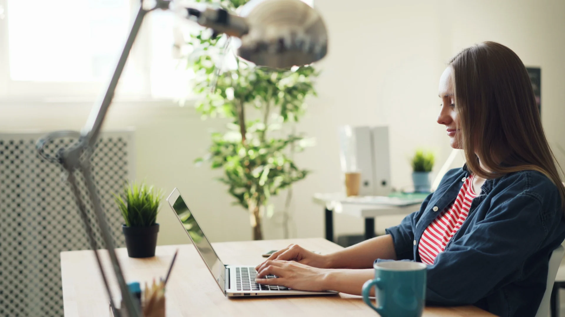 Woman working on a laptop performing a GEO competitive analysis from a home office