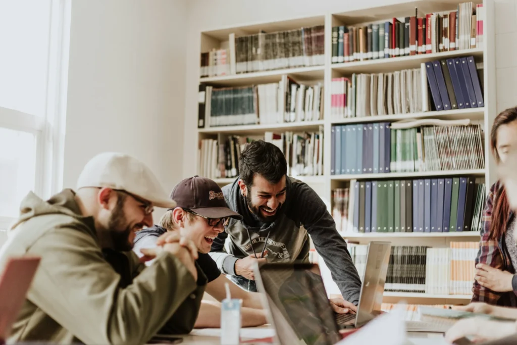 Group of collaborators laughing while researching how to plan content around AI search behaviors on a laptop