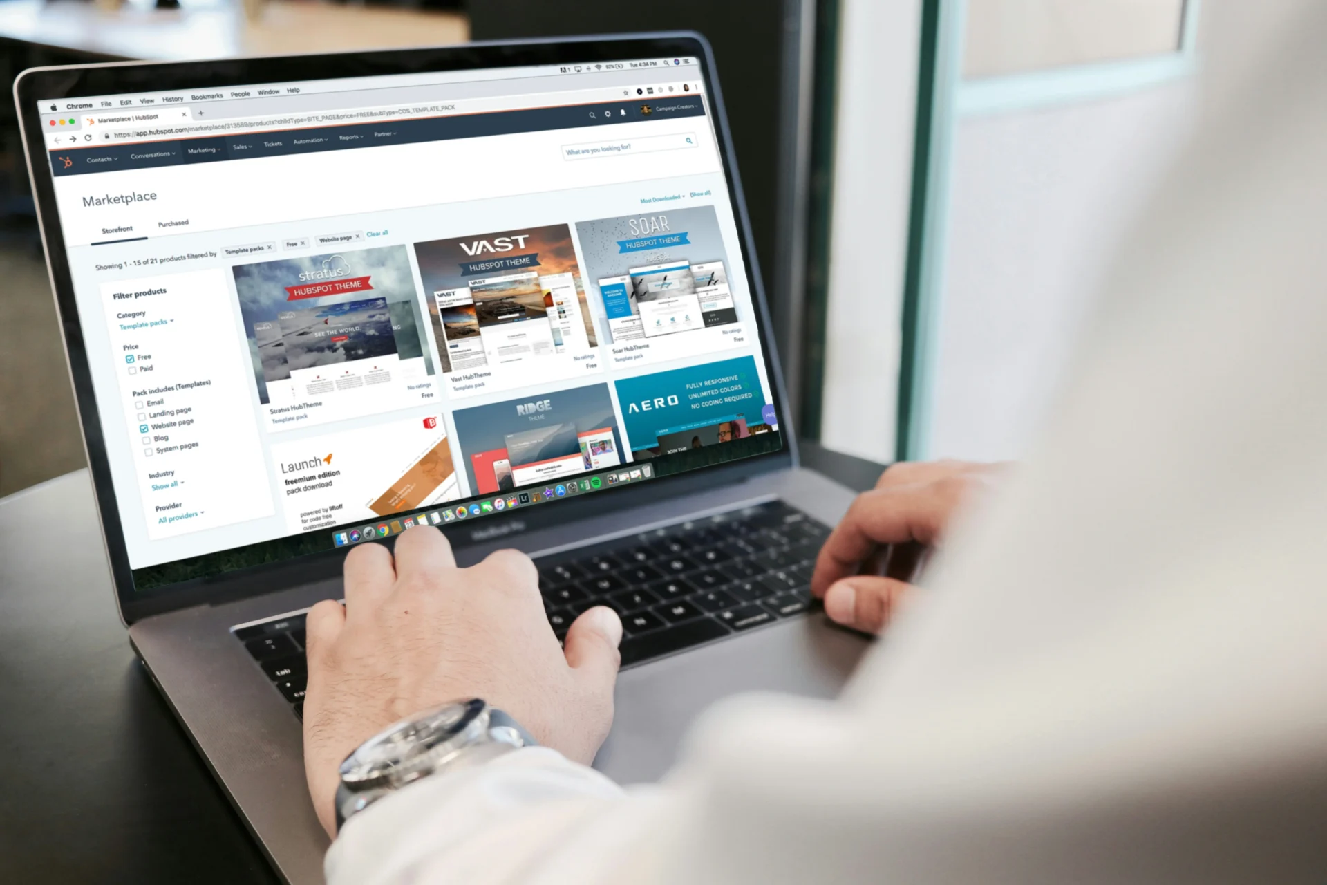 Person typing on a laptop displaying a website template marketplace to structure content for expert quotes and AI citations in GEO.