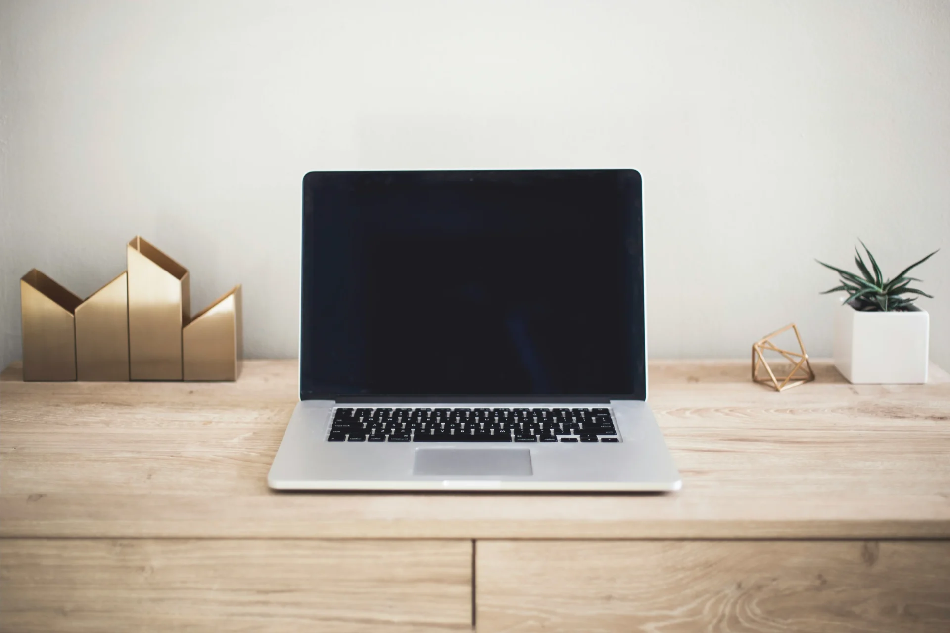 Open laptop sitting on a minimalist wooden desk, representing workspace setup for analyzing common GEO mistakes and content optimization.
