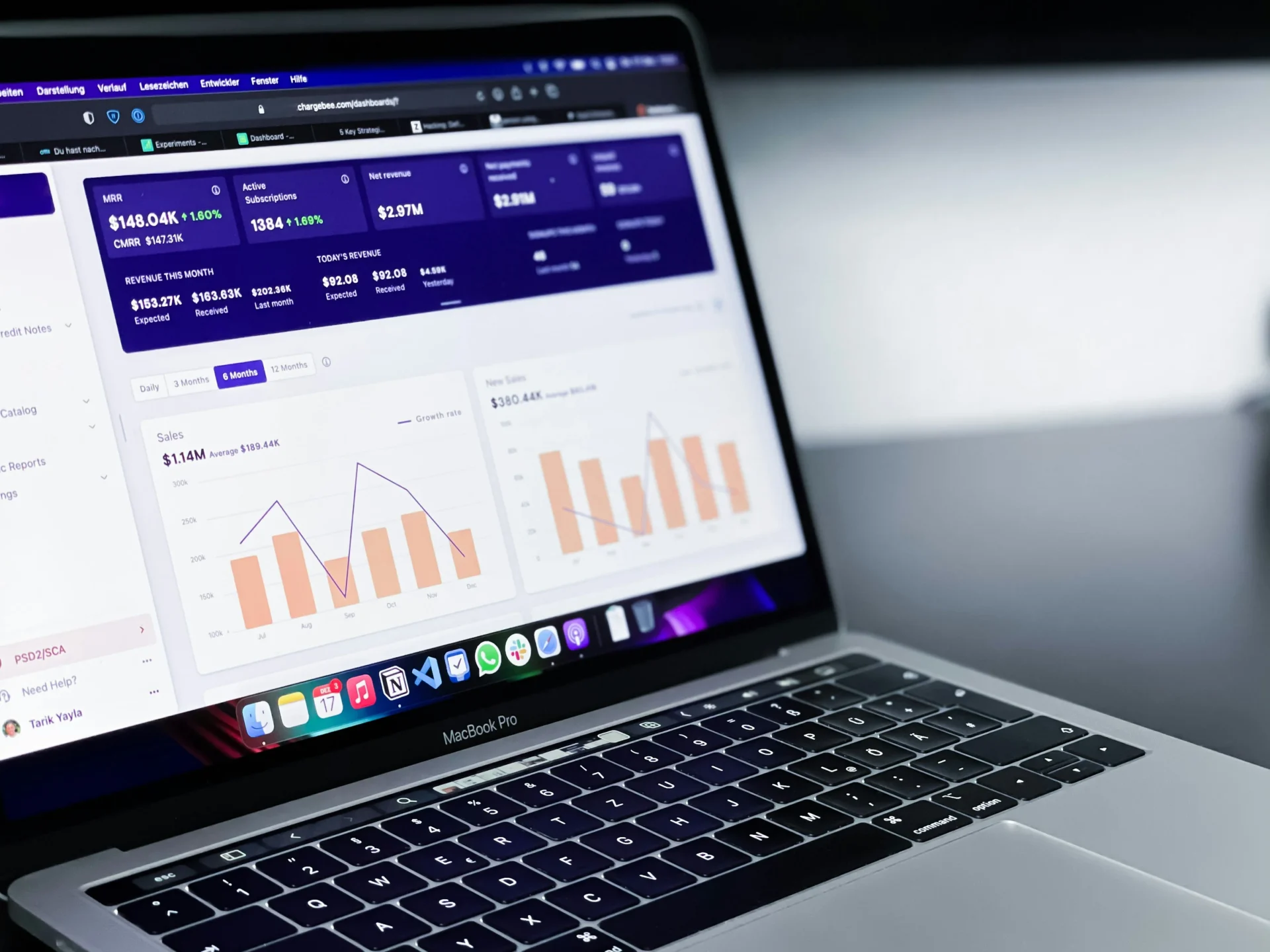Close-up of a MacBook Pro open to a digital dashboard showing sales charts and financial metrics