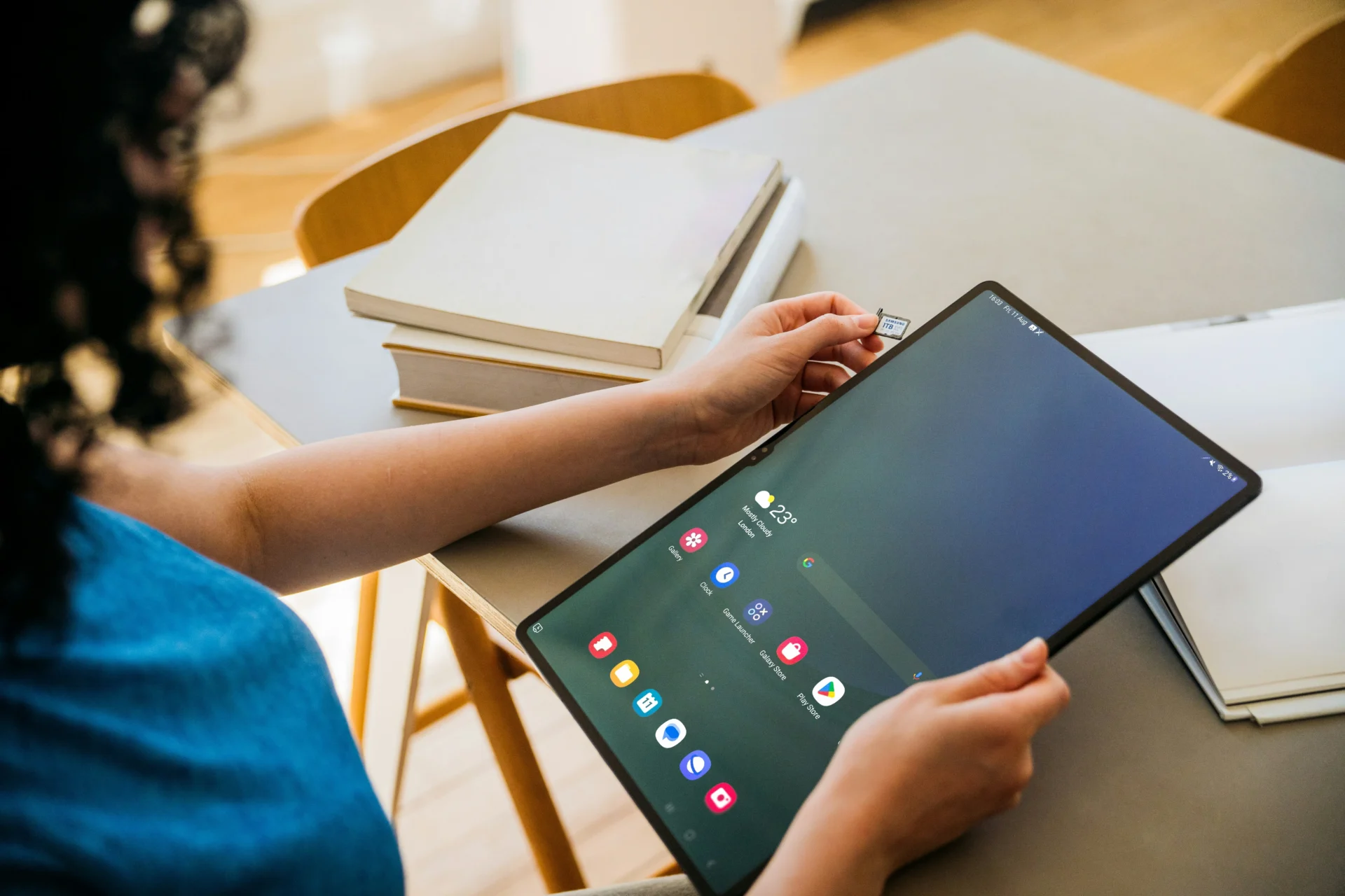 Person holding a large Android tablet and inserting a microSD memory card containing original research for AI citations and GEO assets.